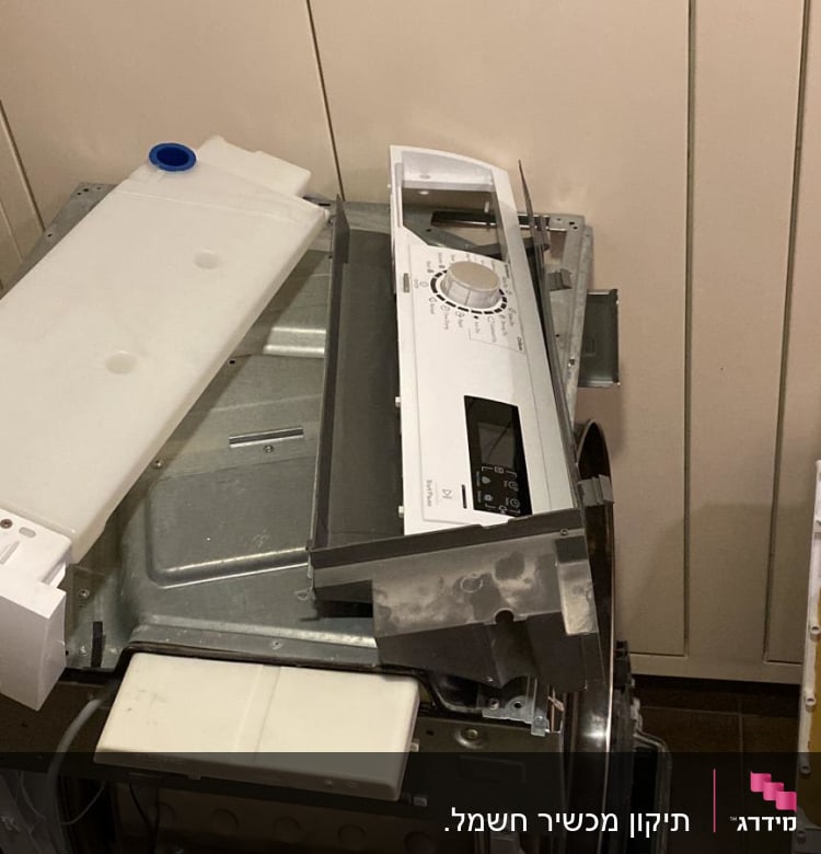 חלקי מכונת כביסה מפורקים, כולל לוח בקרה ומיכל פלסטיק